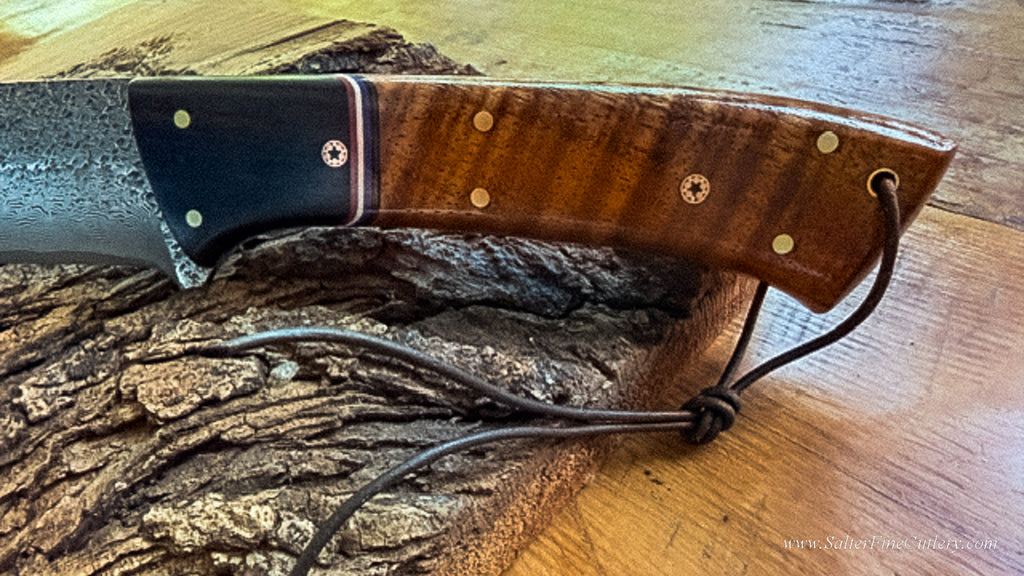 A close-up photo of the handle of our patriotic Stars and Stripes collectible knife featuring Hawaiian curly koa wood and red white and blue stripes with mosic star decorative pins by SalterFineCutlery
