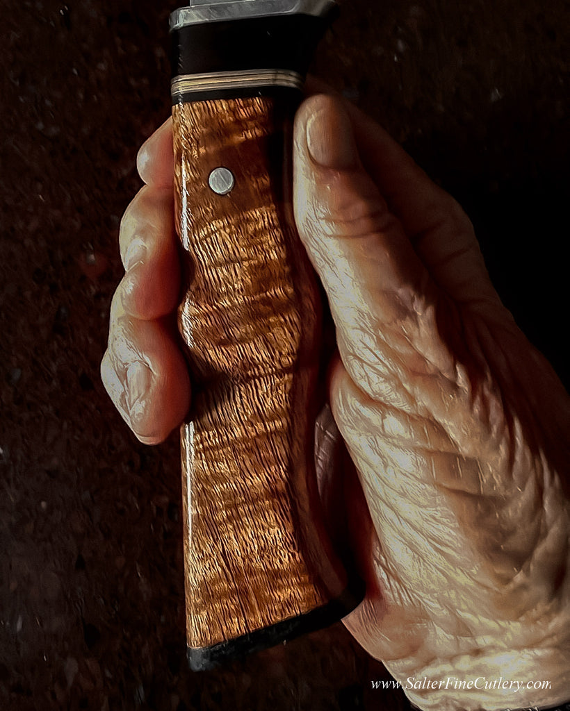 Detail view of decorative handle handmade by SalterFineCutlery featuring Hawaiian curly koa wood with accents of African blackwood  stainless steel brass 